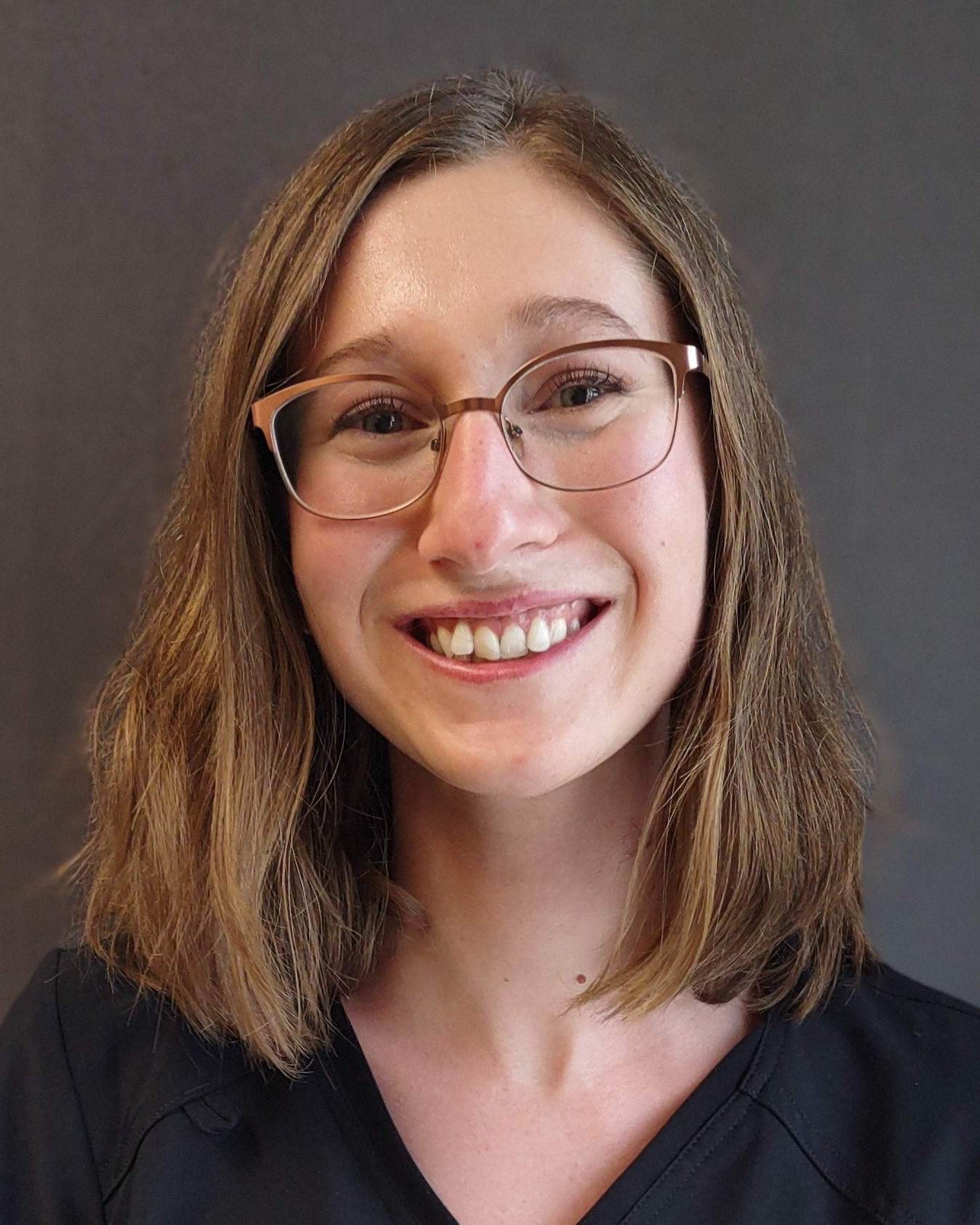 A bespectacled, young white woman with long brown hair all the way up to her elbows